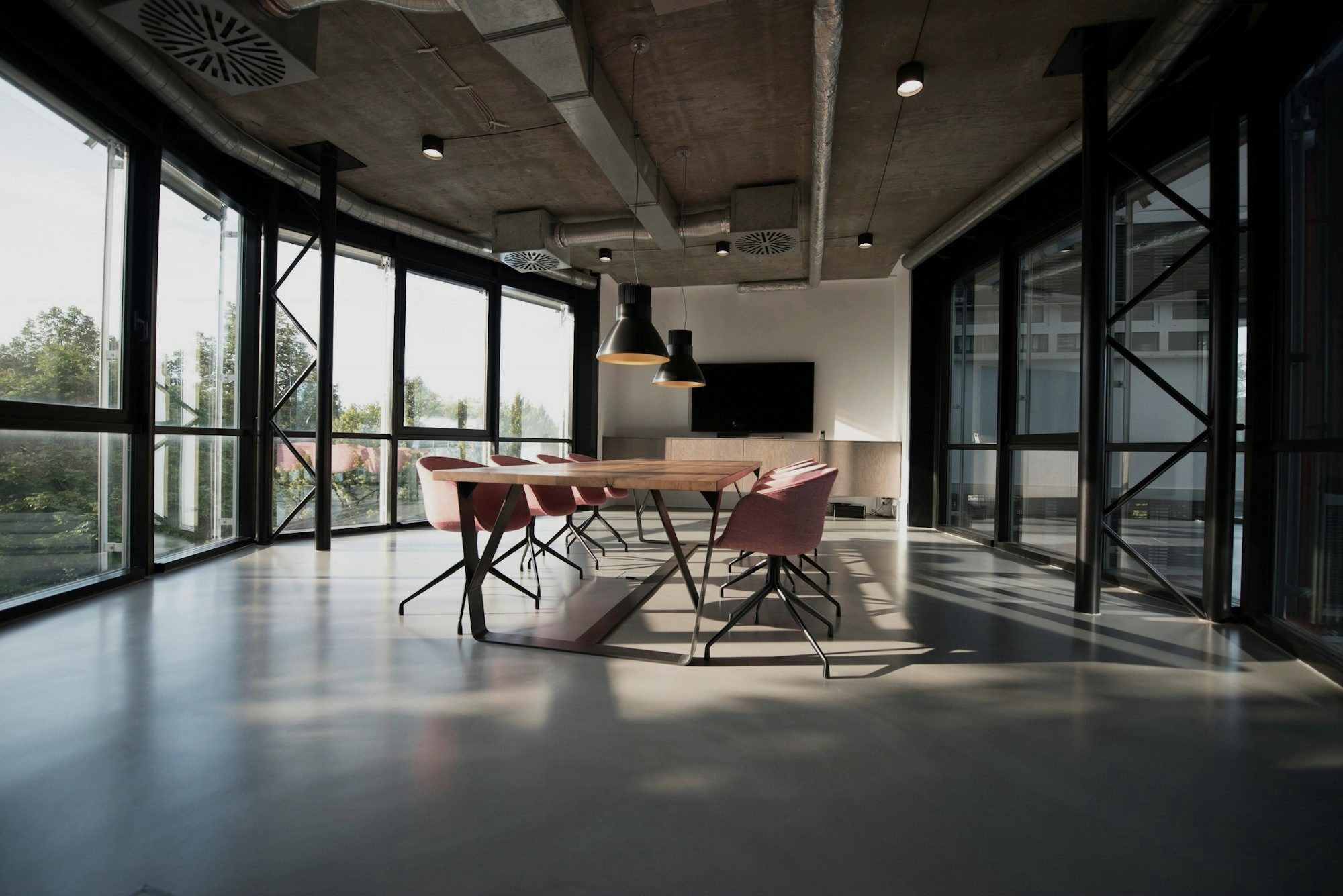 An empty conference room with a long table and tall windows