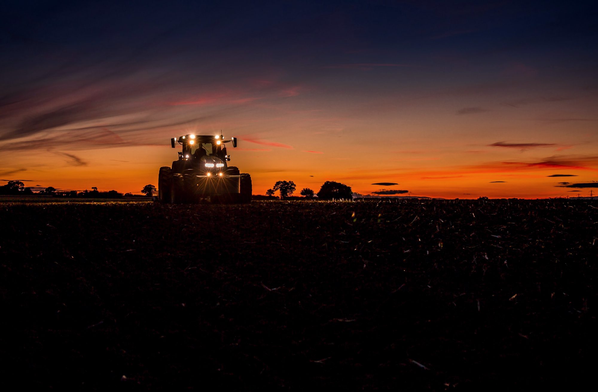 A tractor working a field at sunset