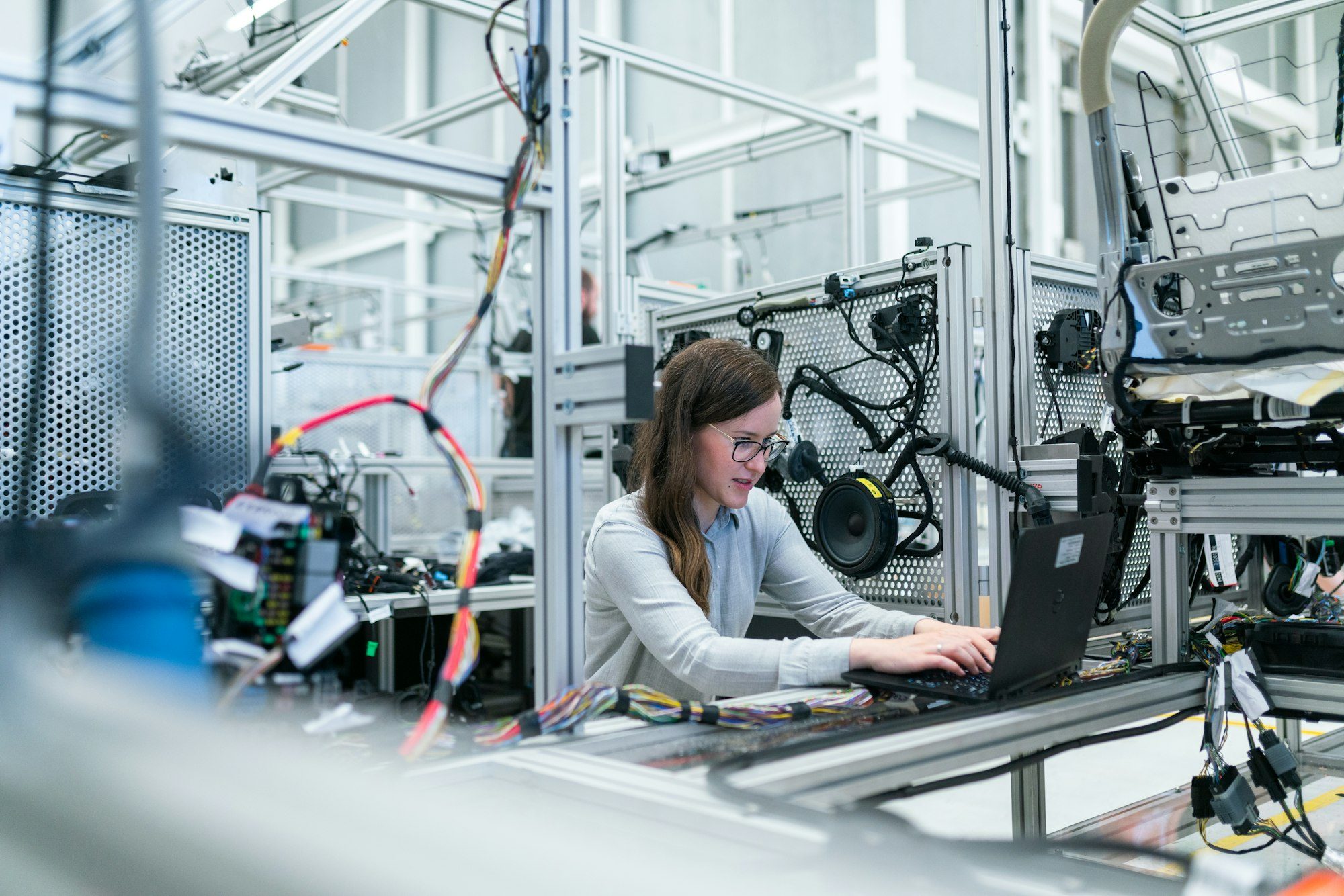 An engineer at a laptop beside a hardware test rig